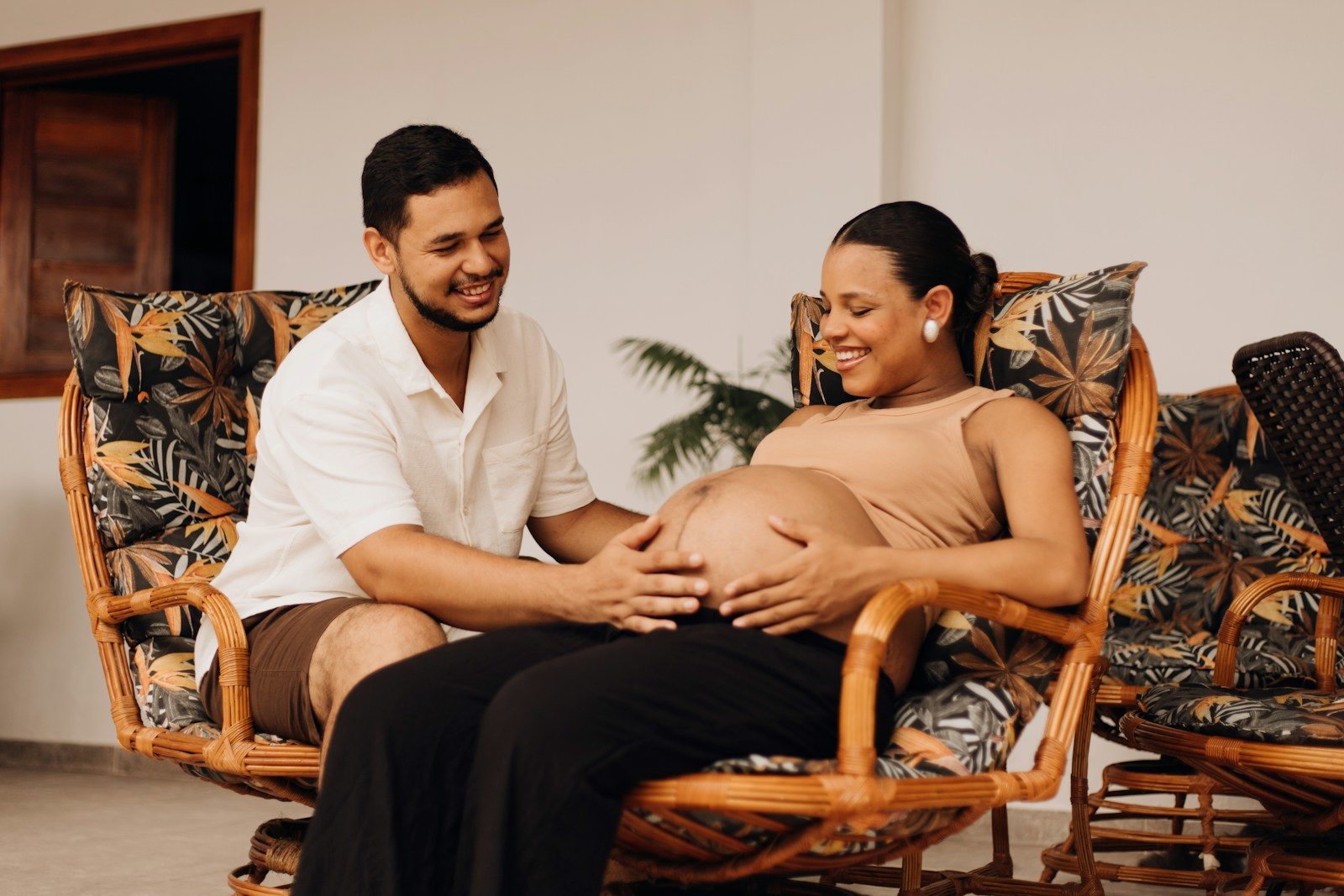 a pregnant woman sitting on a chair next to a man